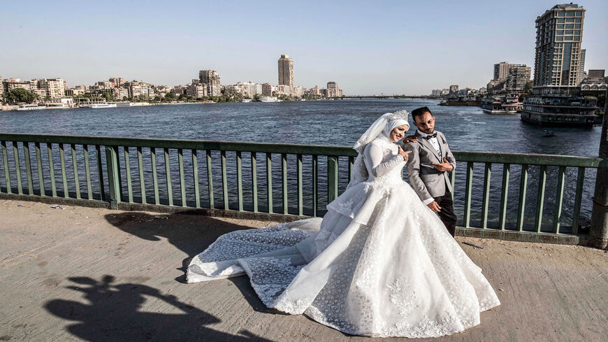 Ragab Uwais poses for a picture with his bride before a video cameraman for their wedding video along Al-Gamaa Bridge connecting Cairo with its twin city of Giza, Egypt, June 11, 2020.