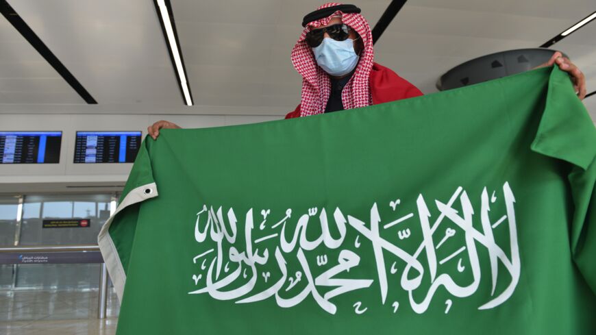 A Saudi man carrying Qatari and Saudi flags waits for the arrival of relatives at King Khalid International Airport in the Saudi capital, Riyadh.