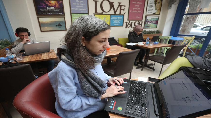 Syrian journalist Zeina Shahla types on her laptop at a cafe, Damascus, Syria, March 1, 2021. 