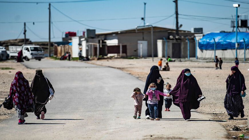 Women with children walk at Roj camp, where relatives of people suspected of belonging to the Islamic State are held, in the countryside near al-Malikiyah (Derik), Hasakah province, Syria, March 28, 2021.