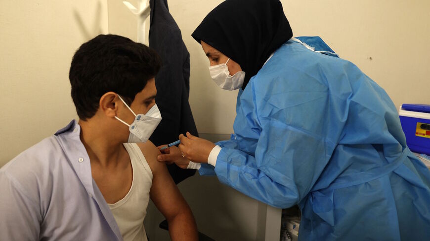 An Iranian health worker inoculates a young man against the coronavirus, at a vaccination centre set up inside the Iran Mall in the capital Tehran, on Aug. 14, 2021.