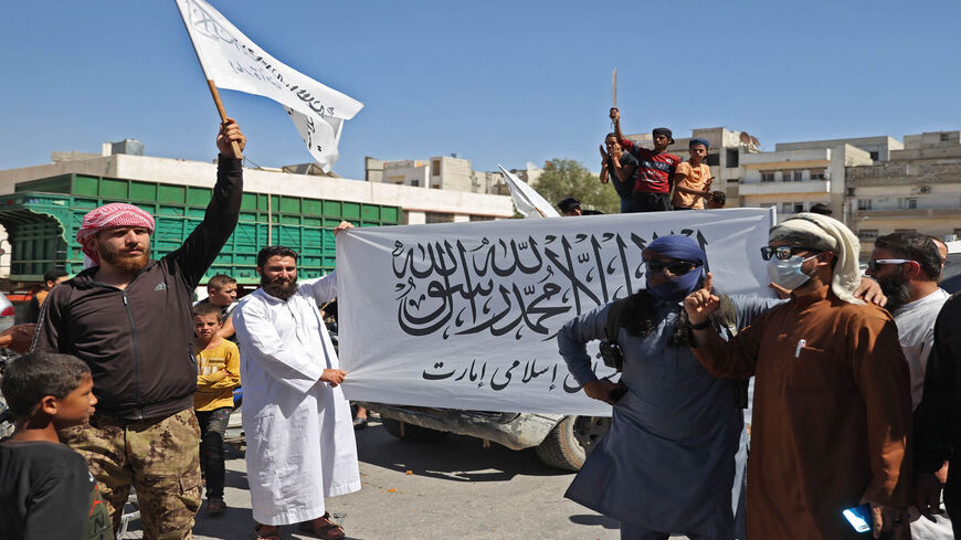 Members of Syria's top jihadist group, Hayat Tahrir al-Sham, led by al-Qaeda's former Syria affiliate, parade with their flags and those of the Taliban's declared "Islamic Emirate of Afghanistan" through the rebel-held northwestern city of Idlib, Syria, Aug. 20, 2021.