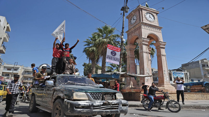 Members of Syria's top jihadist group Hayat Tahrir al-Sham, led by al-Qaeda's former Syria affiliate, parade with their flags and those of the Taliban's declared "Islamic Emirate of Afghanistan" at the Clock Square in the center of the rebel-held northwestern city of Idlib, Aug. 20, 2021.