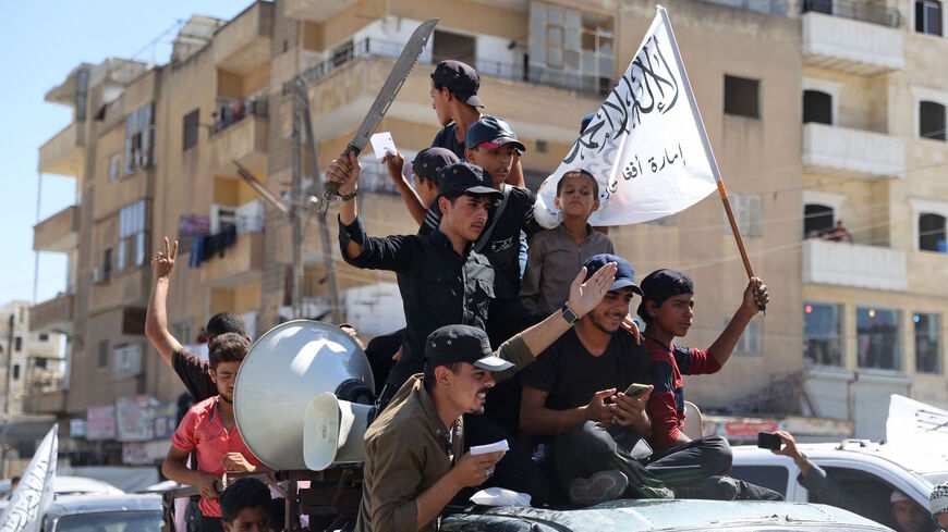 Members of Syria's top jihadist group the Hayat Tahrir al-Sham (HTS) alliance, led by al-Qaeda's former Syria affiliate, parade with their flags and those of the Taliban's declared "Islamic Emirate of Afghanistan" through the rebel-held northwestern city of Idlib on Aug. 20, 2021. 