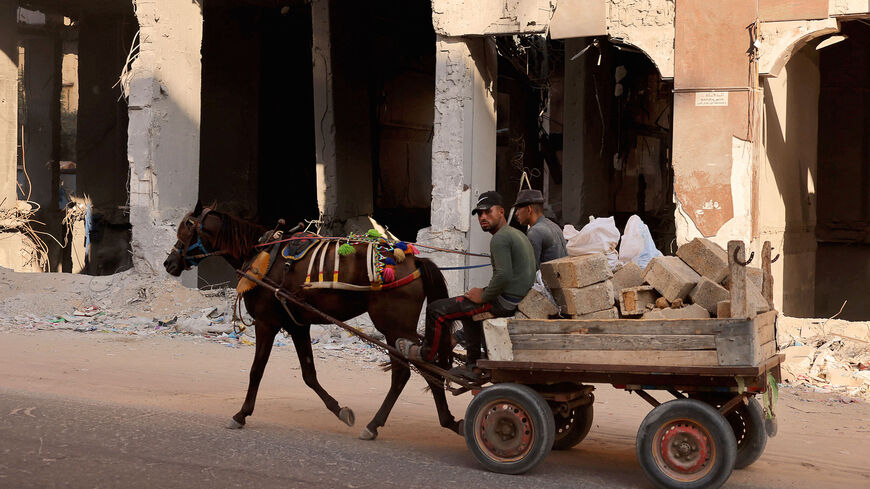 Palestinians ride a horse cart carrying rubble past the ruins of buildings destroyed in the lasted round of Israeli-Hamas fighting, in Gaza City, on Aug. 25, 2021.