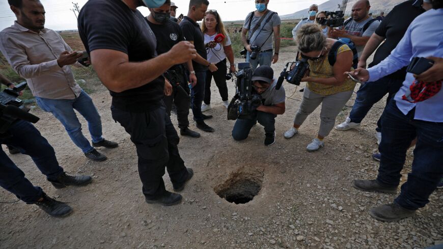 Police and journalists gather around a hole used by six Palestinians to escape from the Gilboa Prison after they dug a tunnel beneath a sink, in northern Israel on Sept. 6, 2021.  