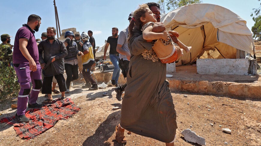 A man carries away a girl who was injured during aerial bombardment at a camp for displaced Syrians near the town of Kafraya in the north of Syria's rebel-held Idlib province on Sept. 7, 2021. 