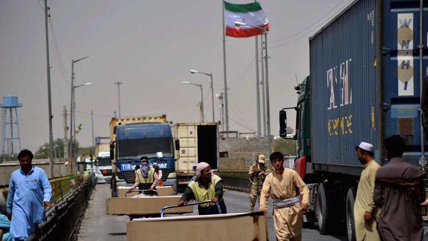 People push carts loaded with coffins of Afghan nationals who died in Iran after receiving them at an Afghan-Iran border crossing in Zaranj on Sept. 8, 2021.