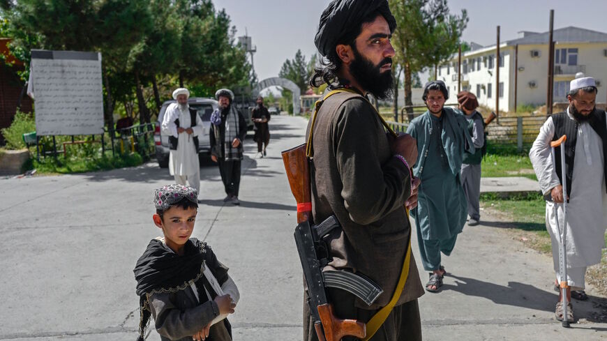 An Afghan boy stands next to a member of the Taliban in front of the Pul-e-Charkhi prison in Kabul on Sept. 16, 2021. 