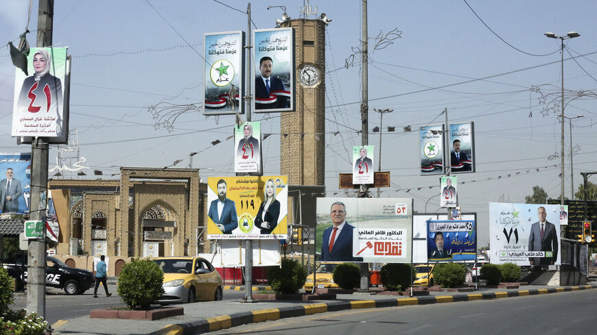 Iraqis go about their day beneath electoral billboards and placards of candidates for the upcoming parliamentary elections, in the district of Adhamiyah in the capital Baghdad, on Sept. 17, 2021.