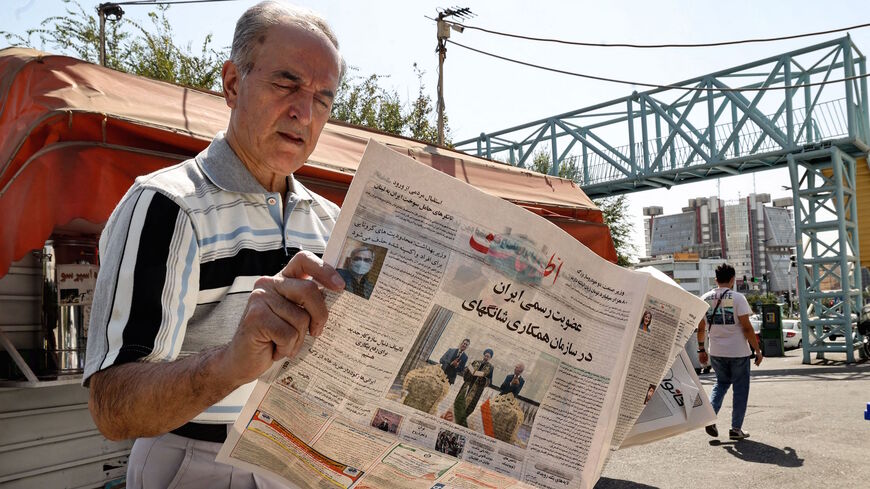 An Iranian man reads a copy of the daily newspaper "Etalaat" bearing the headline "Iran is a new member of the Shanghai Cooperation Organisation", at a kiosk in the capital Tehran, on Sept. 18, 2021. 