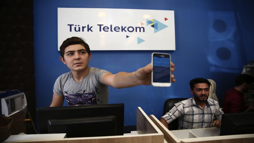 A shop owner selling Turk Telekom phone lines is pictured holding a phone in the northern city of Azaz.