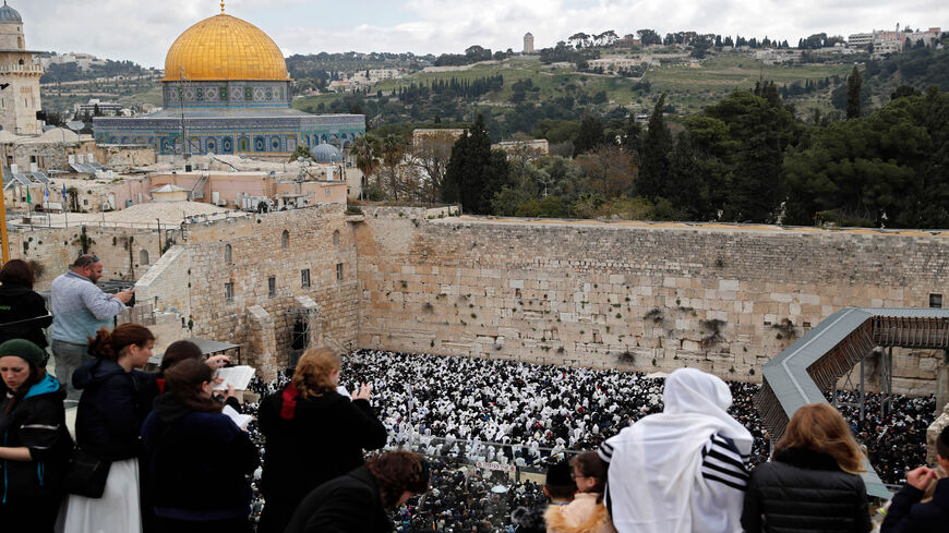 Pious Jews join prayers from a terrace overlooking the spot where Jewish priests covered with black and white Talit prayer shawls perform the Cohanim prayer at the Western Wall, with the Dome of the Rock shrine seen in the background, during the Passover holiday, Old City of Jerusalem, April 22, 2019.