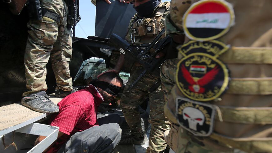 Iraq's rapid response forces detain a man as they storm a house in the Tarmiya district.