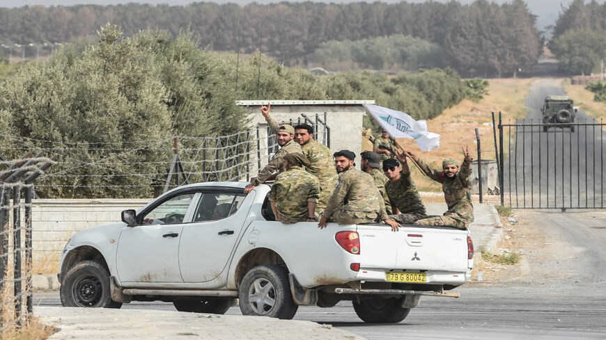 Members of the Turkish-backed Free Syrian Army wave on top of a vehicle as they drive back to their base camp, Akcakale, Turkey,  Oct. 16, 2019.