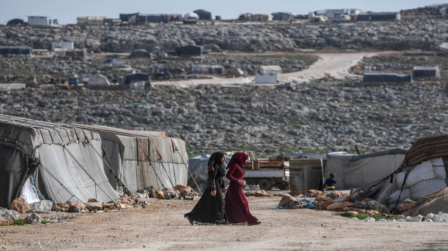 Displaced Syrian women walk at a camp in Kafr Lusin village on the border with Turkey in the northwestern province of Idlib, Syria, March 10, 2020.
