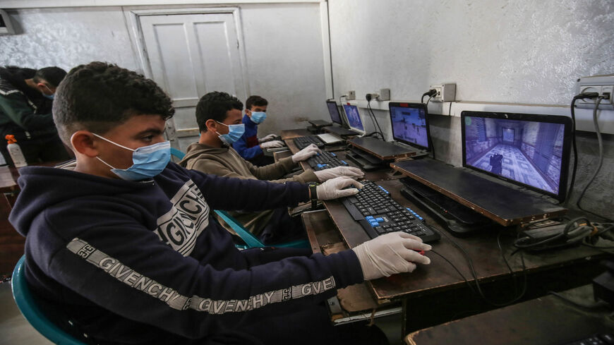 Palestinian children wearing protective face masks as a preventive measure against the spread of the coronavirus play video games in Rafah, Gaza Strip, March 22, 2020.