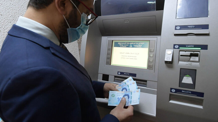 A man retrieves newly circulating Tunisian bank notes from an ATM, Tunis, Tunisia, March 27, 2020.