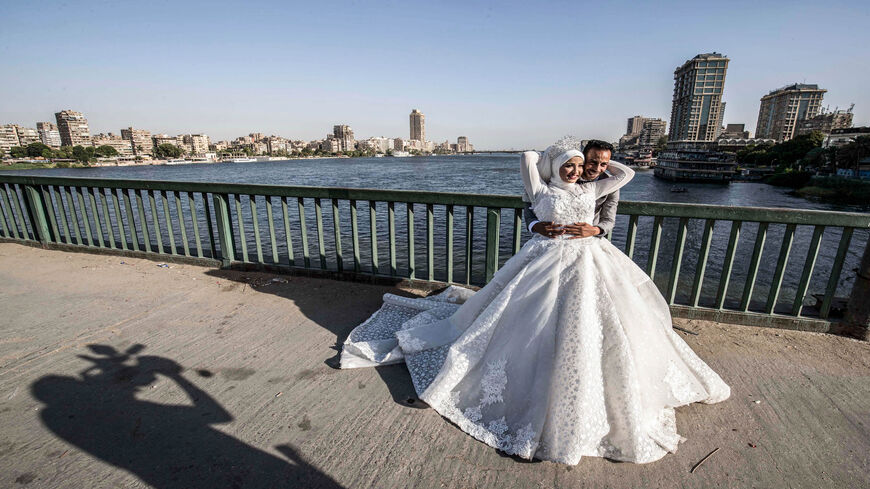 Ragab Uwais poses for a picture with his bride before a video cameraman for their wedding video along Al-Gamaa Bridge connecting the Egyptian capital Cairo with its twin city of Giza, Egypt, June 11, 2020.