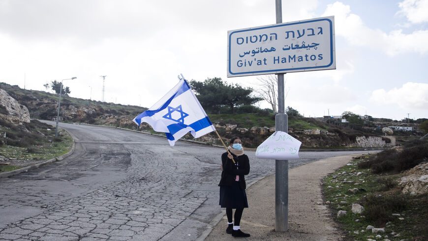 An Israeli woman holds the Israeli flag at the entrance to Givat HaMatos, Jerusalem, Nov. 16, 2020.
