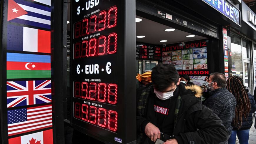 Customers wait in front of a currency exchange agency as a screen shows rates near the Grand Bazaar, in Istanbul, on March 22, 2021.