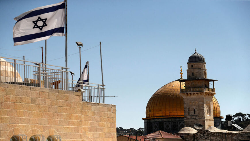 This picture shows an Israeli flag fluttering above a building near the Dome of the Rock mosque in the Old City of Jerusalem, July 18, 2021.