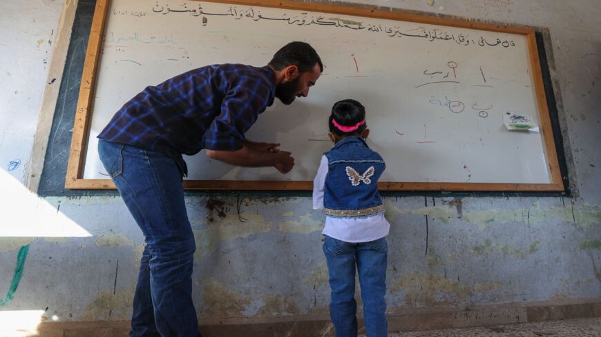 A teacher helps a child during the first day of school in a village in the countryside of Syria's northwestern Idlib province on Oct. 9, 2021.