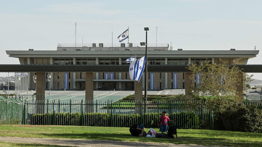 People sit in a garden in front of the Knesset, Jerusalem, Oct. 17, 2021.