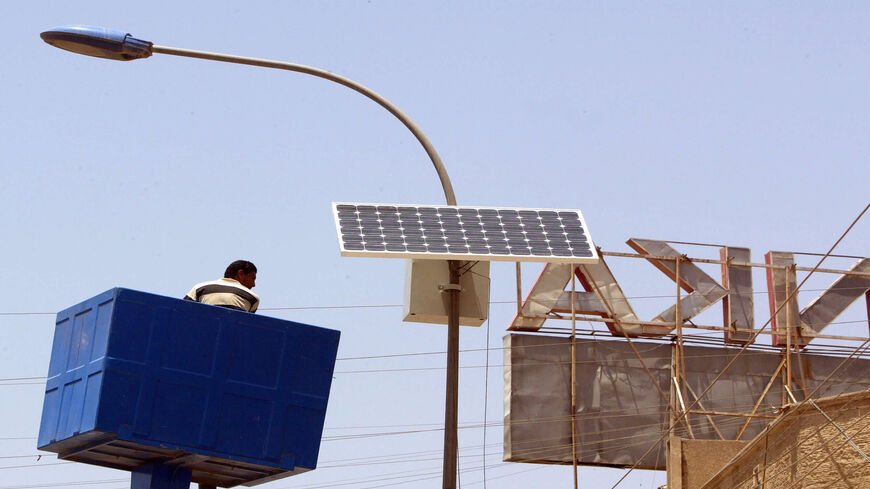 A municipal worker is lowered after adjusting a solar panel attached to the top of an electricity pylon along the central isle of a main road in Karada district, Baghdad, Iraq, May 24 2008.