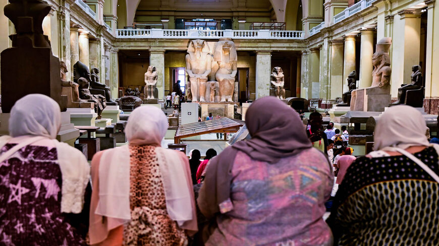 A group of women sit in front of the Colossal statue of Amenhotep III and Tiye at the Cairo Museum, Cairo, Egypt, July 15, 2019.