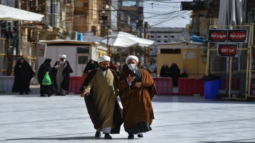 An Iraqi cleric walks alongside another in the central holy city of Najaf, on Feb. 26, 2020.