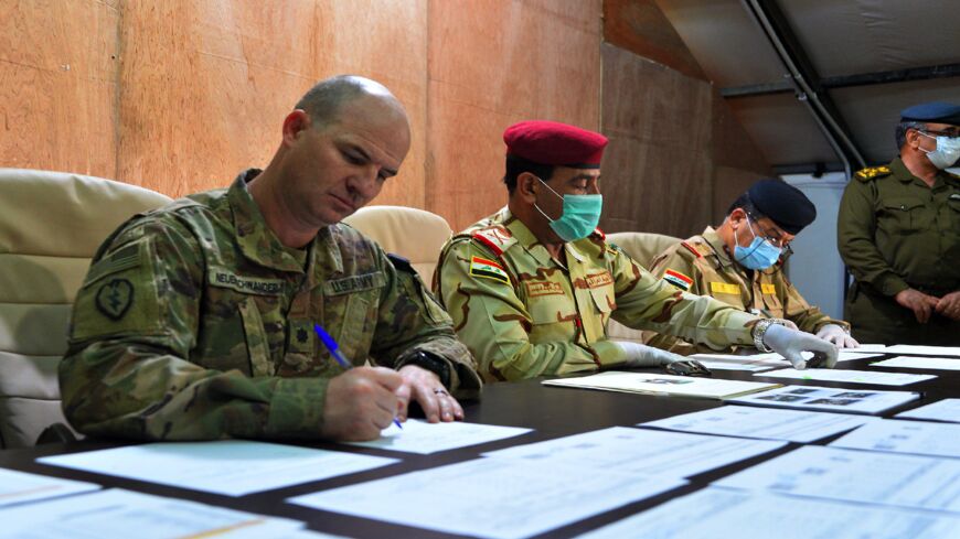 US Army Cmdr. Jace Neuenschwander (L) and Iraq Nineveh Operations Cmdr. Maj. Gen. Noman Zawbai (C) and Iraq's Staff Maj. Gen. Mohammad Fadhel Abbas sign documents.