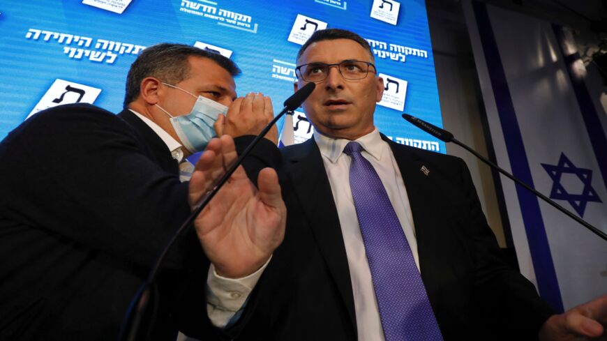 An aide whispers to Gideon Saar (R), leader of Israel's Tikva Hadasha (New Hope) party, as he addresses supporters at his party's campaign headquarters.