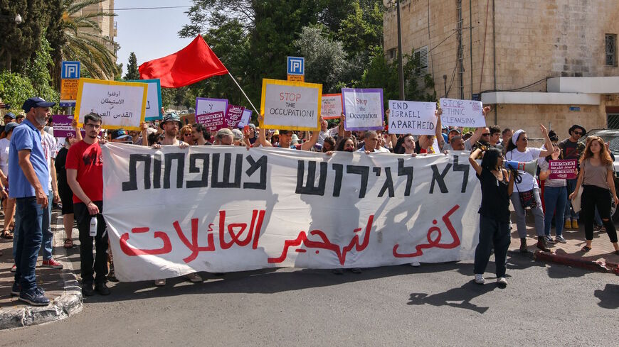 Israeli, Palestinian and foreign activists, hold a banner that reads in Arabic and Hebrew:"Stop the expulsion of families", during a demonstration against Israeli occupation and settlement activity in the Palestinian territories and east Jerusalem, near the Israeli police checkpoint at the entrance of the Shiekh Jarrah neighbourhood, on June 11, 2021. 