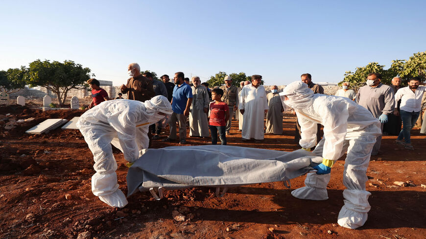 Paramedics transport the corpse of a Syrian who died of the coronavirus during a funeral in the village of Barisha, Idlib province, Syria, Sept. 30, 2021.