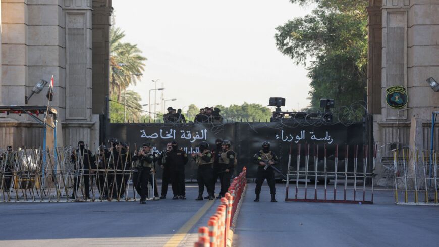 Members of Iraqi security stand guard as supporters of the Hashid al-Shaabi paramilitary network march toward one of the Green Zone entrances in the capital, Baghdad, on Nov. 6, 2021.