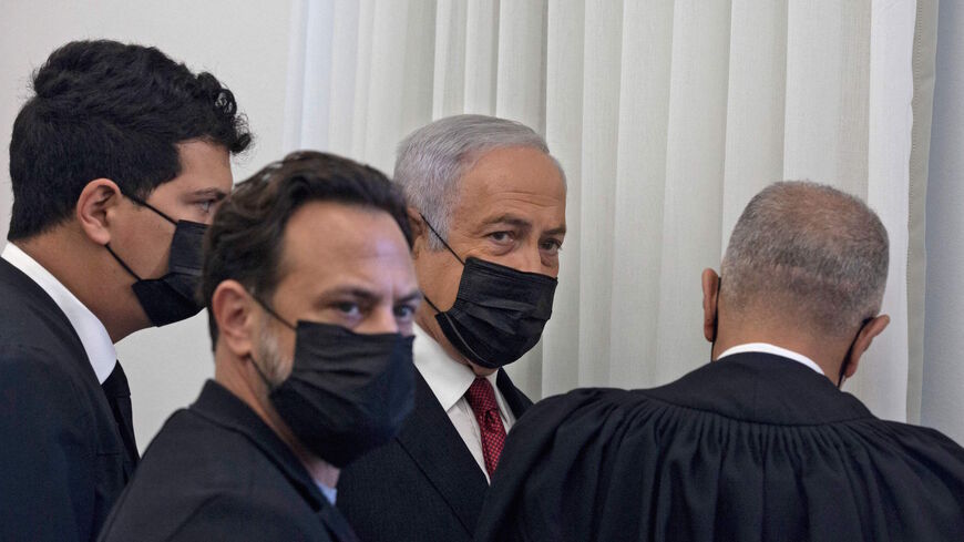 Former Israeli Prime Minister Benjamin Netanyahu (C) is flanked by lawyers before testimony by star witness Nir Hefetz, a former aide, in his corruption trial at the District Court in east Jerusalem, on Nov. 22, 2021.