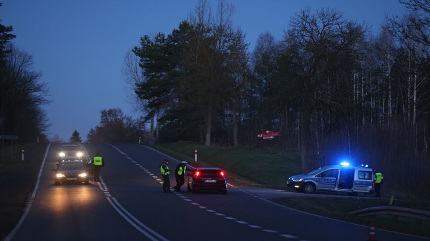 Police check approaching vehicles at a checkpoint along a road leading toward the border with Belarus on Nov. 10, 2021, near Kuznica, Poland.