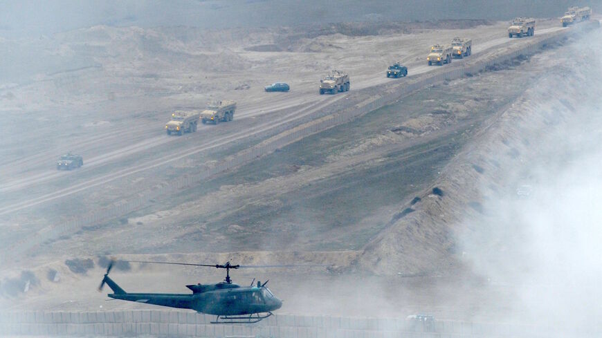 A UH-1H helicopter flies over armored vehicles during a military drill at a base near the town of Gardabani, south of Tbilisi, on Jan. 23, 2015. 