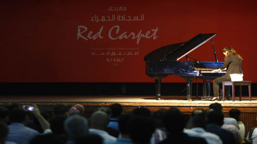 A woman plays the piano on stage during the opening of the "Red Carpet" cinema festival in Gaza City, Gaza Strip, May 12, 2016.