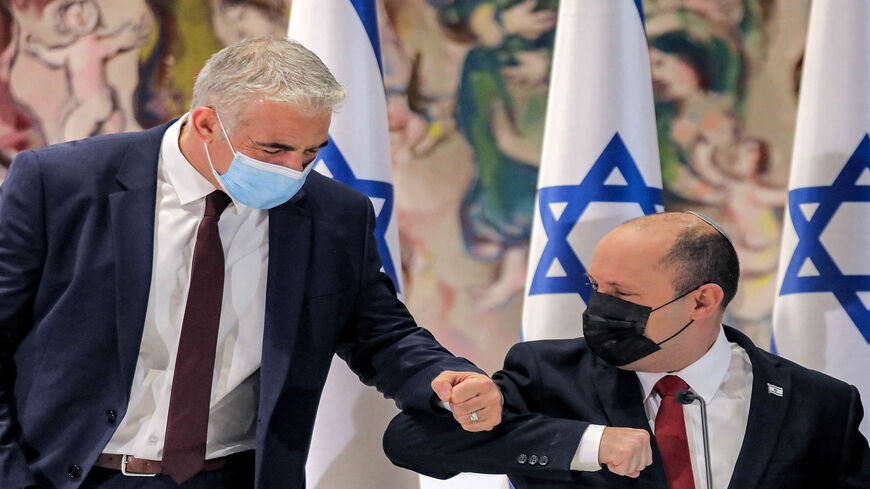 Israeli Prime Minister Naftali Bennett (R) elbow-bumps Alternate Prime Minister and Foreign Minister Yair Lapid before the start of the weekly Cabinet meeting in the Knesset building, Jerusalem, July 19, 2021.