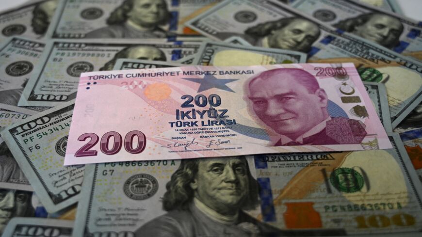 A picture taken on Dec. 7, 2021, in Istanbul shows US dollars banknotes and Turkish lira banknotes. 