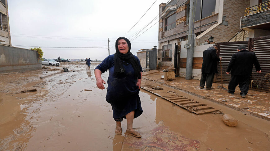 A resident reacts as she walks down a debris-filled street in the area of Daratu, on the outskirts of Erbil, after flash floods caused by torrential rains left eight people dead, Iraqi Kurdistan, Dec. 17, 2021.