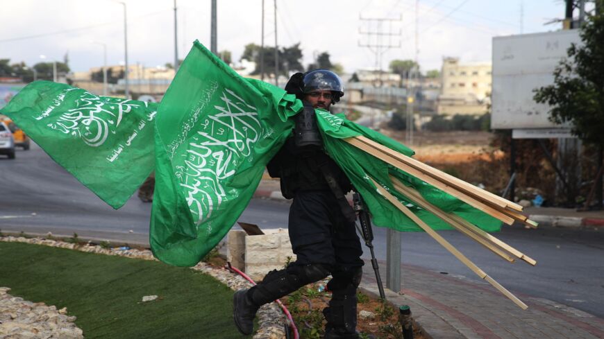 A member of Israel's security forces carries flags of Hamas that were seized during clashes with Palestinian protesters north of Ramallah in the West Bank, on Oct. 8, 2015.