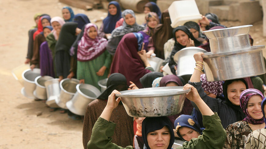 Egyptian women line up at a water cistern (unseen) to fill their containers with clean water at al-Rahawe village, some 40 kilometers (25 miles) northeast of Cairo, Egypt, May 27, 2010.