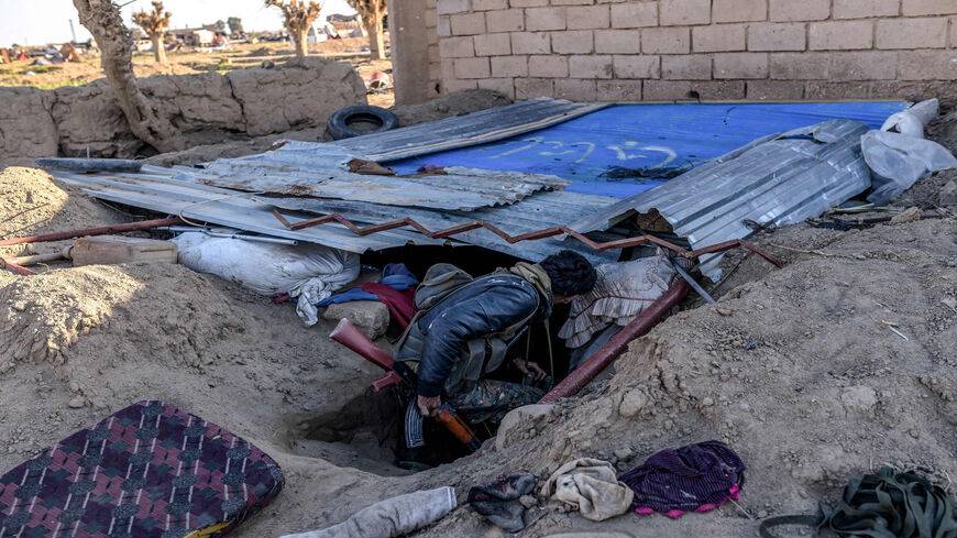 A fighter with the Syrian Democratic Forces inspects a makeshift shelter dug in a trench at a makeshift camp for Islamic State members and their families in the town of Baghouz, Deir Ez-zor, Syria, March 9, 2019.