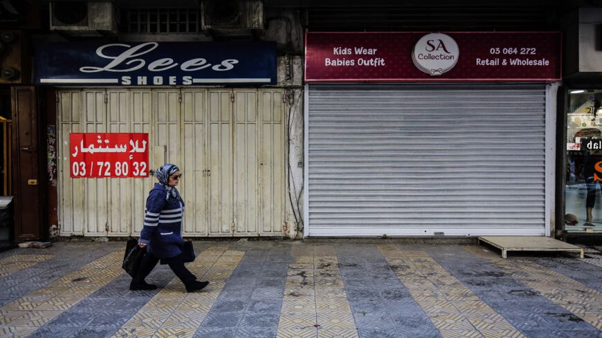 A Lebanese woman walks past closed stores in the northern city of Tripoli on Feb. 25, 2020.