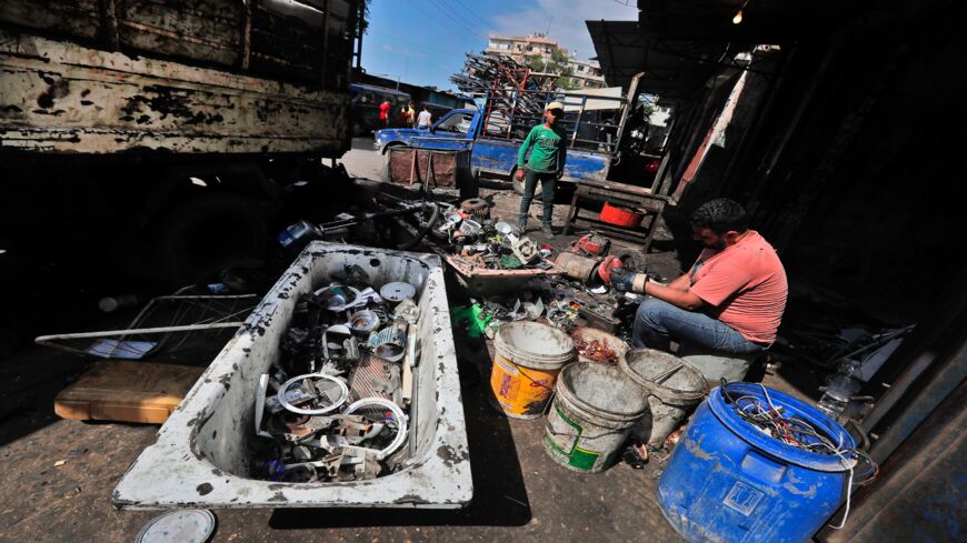 A man sorts through discarded electric devices at a scrap workshop in Lebanon's northern city of Tripoli on June 3, 2020.