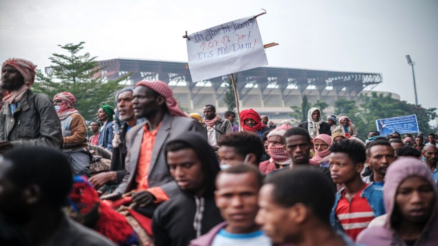 A supporter of Ethiopian Prime Minister Abiy Ahmed holds a sign referring to the Grand Ethiopian Renaissance Dam as a crowd waits to enter the stadium in Jimma, June 16, 2021.