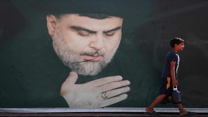 An Iraqi child walks past a poster of Shiite cleric Muqtada al-Sadr in Sadr City in Baghdad on Oct. 17, 2021.